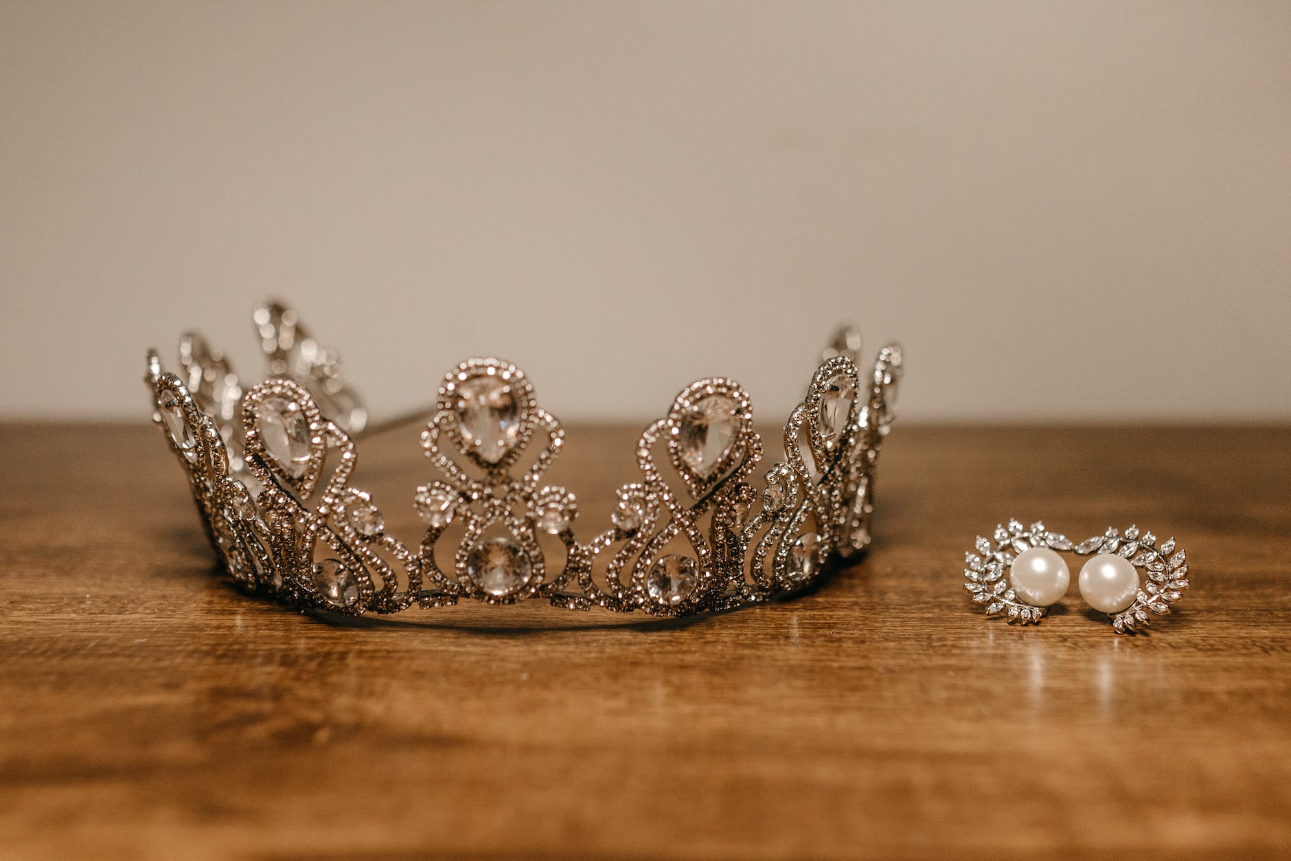 crown and earrings placed on wooden table
